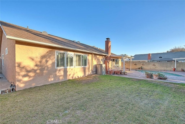 rear view of house with a patio area, cooling unit, and a yard