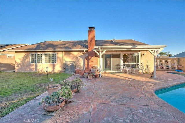 back of house with a fenced in pool, a patio area, cooling unit, and a lawn