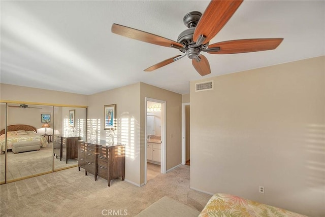 bedroom with ceiling fan, ensuite bath, a closet, and light colored carpet