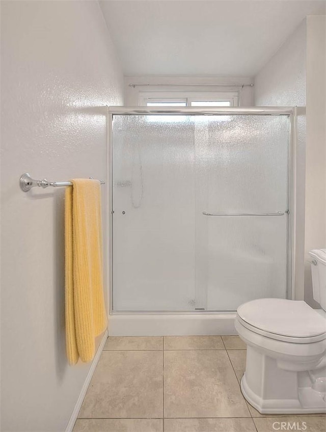 bathroom featuring toilet, a shower with door, tile patterned floors, and lofted ceiling