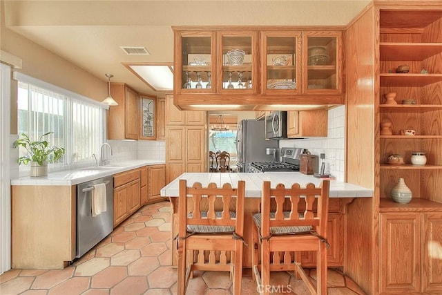 kitchen with backsplash, tile countertops, kitchen peninsula, sink, and stainless steel appliances