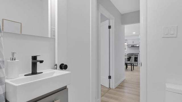 bathroom featuring toilet, hardwood / wood-style flooring, vanity, and decorative backsplash