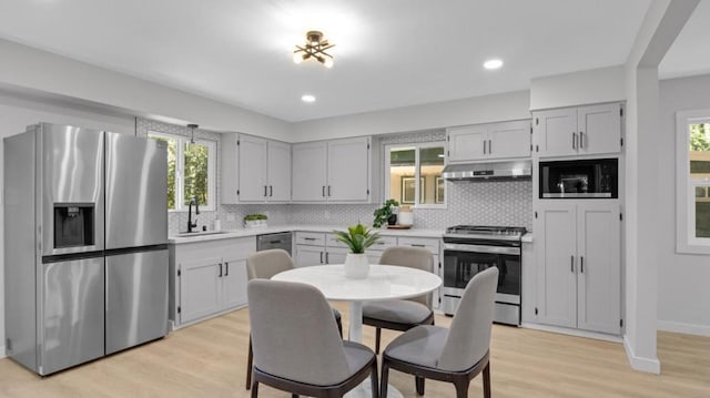 kitchen featuring appliances with stainless steel finishes, tasteful backsplash, light wood-type flooring, and sink