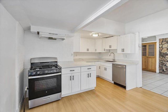 kitchen with sink, white cabinets, light hardwood / wood-style flooring, and stainless steel appliances