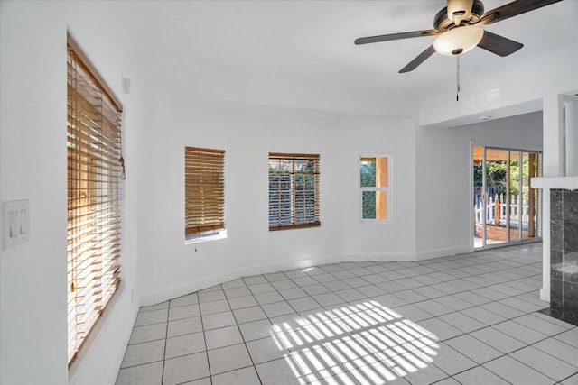 tiled spare room with ceiling fan and a tiled fireplace