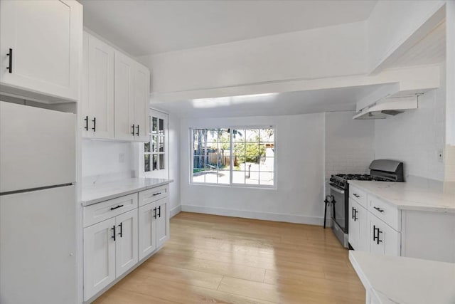 kitchen with white fridge, white cabinetry, light hardwood / wood-style floors, and stainless steel gas stove