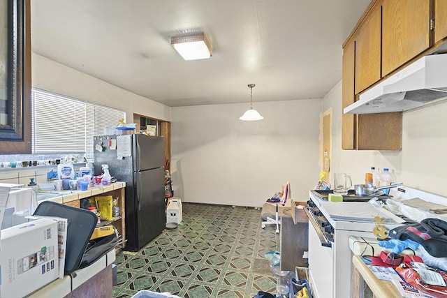 kitchen with pendant lighting, black fridge, and gas range gas stove