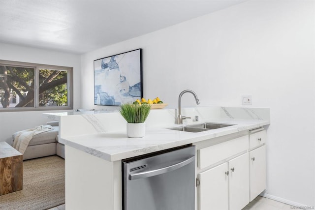 kitchen featuring kitchen peninsula, stainless steel dishwasher, light stone countertops, white cabinets, and sink