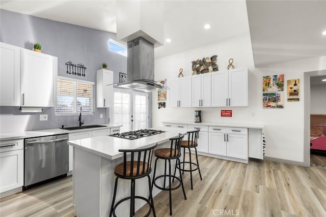 kitchen with sink, island exhaust hood, stainless steel appliances, and white cabinetry