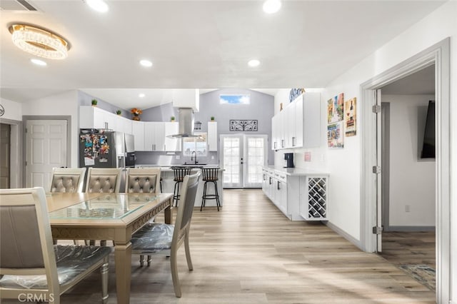 dining space featuring sink, lofted ceiling, french doors, and light wood-type flooring