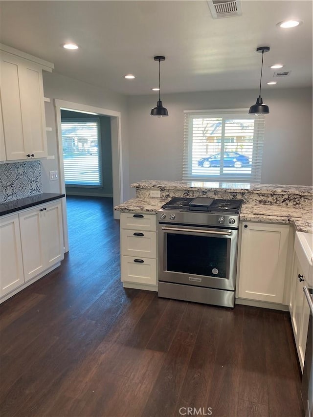 kitchen featuring gas range, backsplash, pendant lighting, and white cabinets