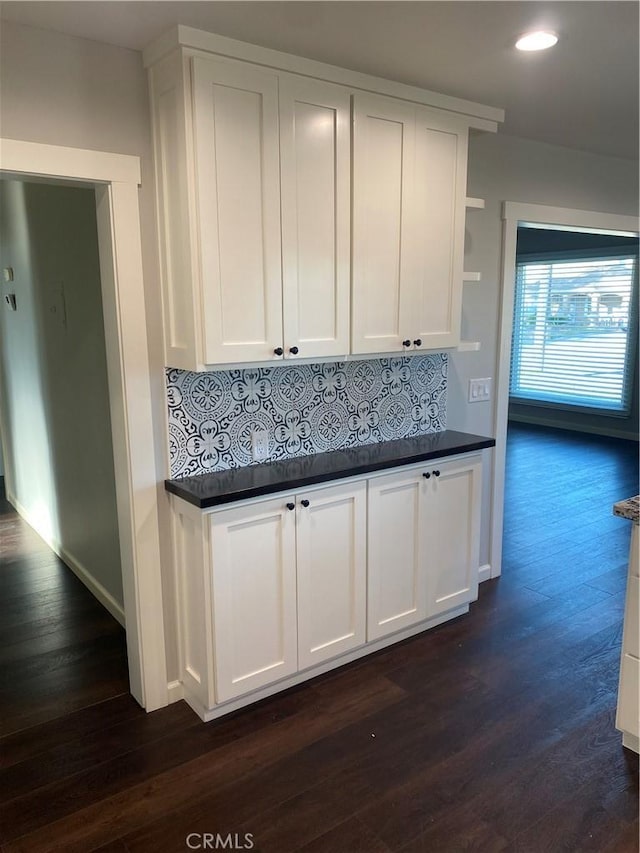 kitchen with decorative backsplash, dark wood-type flooring, and white cabinets