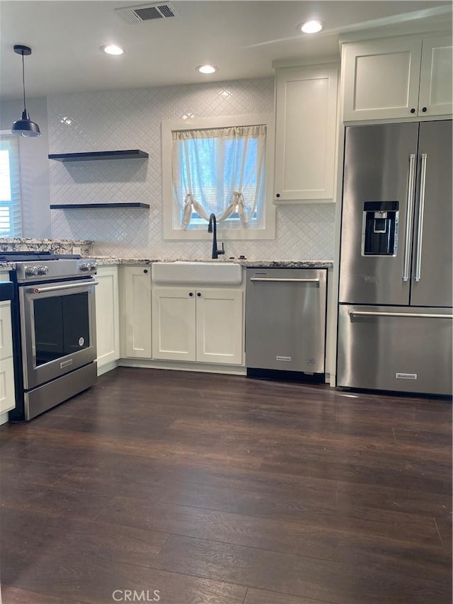 kitchen with stainless steel appliances, white cabinetry, hanging light fixtures, and sink