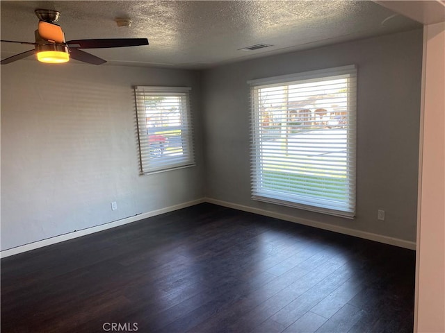 spare room with a textured ceiling, dark wood-type flooring, and ceiling fan