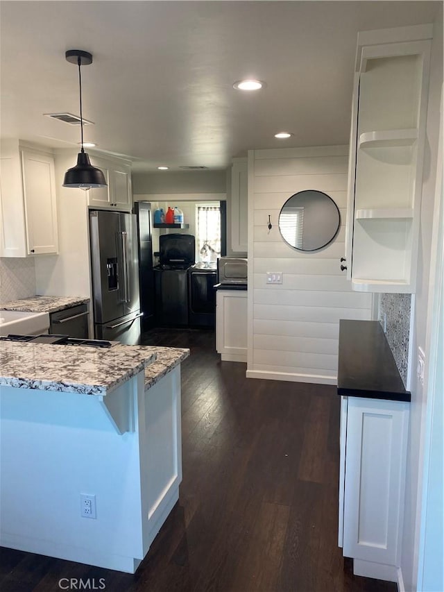 kitchen with appliances with stainless steel finishes, backsplash, dark hardwood / wood-style flooring, hanging light fixtures, and white cabinets