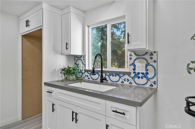 kitchen with decorative backsplash, sink, white cabinetry, and a healthy amount of sunlight