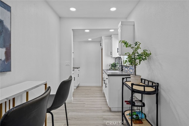 kitchen featuring white cabinets, light wood-type flooring, and sink