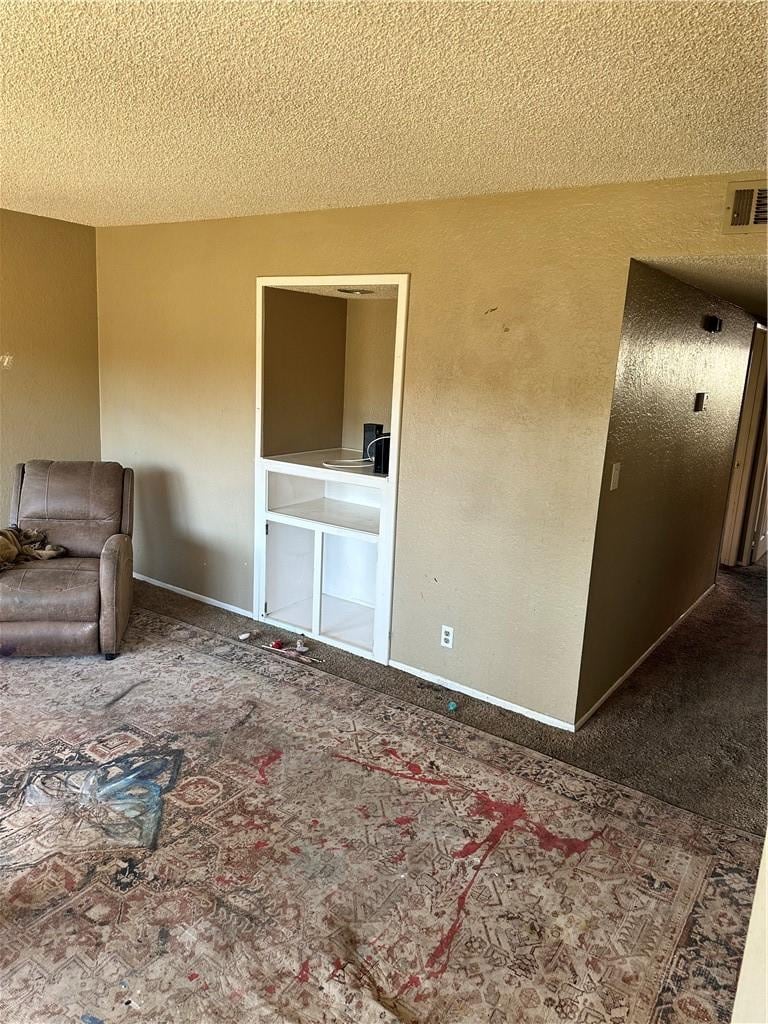 unfurnished living room featuring carpet floors and a textured ceiling