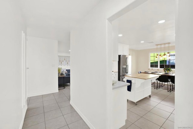 kitchen featuring light tile patterned flooring, white cabinetry, hanging light fixtures, and stainless steel fridge with ice dispenser