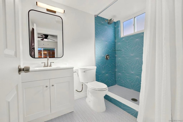 bathroom with vanity, tiled shower, toilet, and ceiling fan