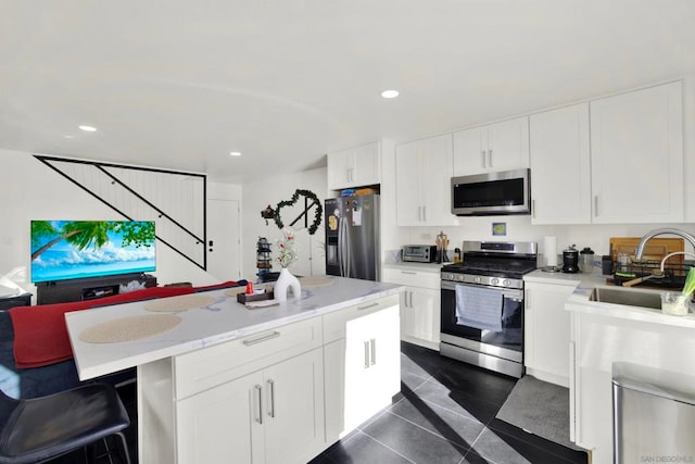 kitchen featuring a center island, appliances with stainless steel finishes, dark tile patterned flooring, and white cabinetry