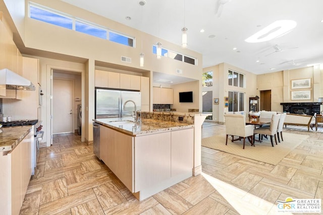 kitchen featuring a large island, a towering ceiling, appliances with stainless steel finishes, and decorative light fixtures