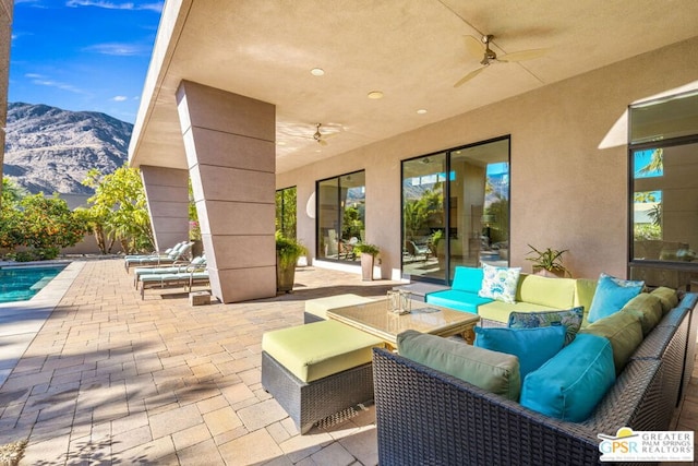 view of patio with an outdoor living space, a mountain view, and ceiling fan