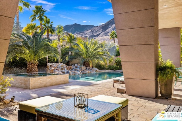 view of swimming pool with an in ground hot tub, a mountain view, and a patio area