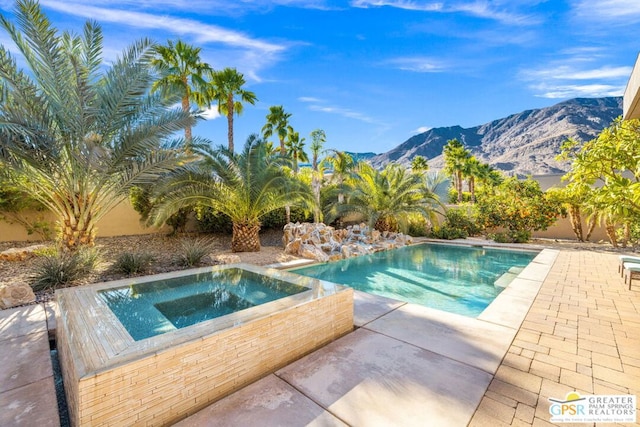 view of pool featuring an in ground hot tub, a mountain view, and a patio area