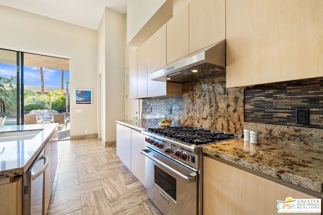 kitchen featuring sink, appliances with stainless steel finishes, tasteful backsplash, extractor fan, and light stone countertops