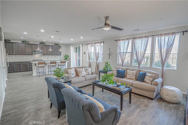 living room featuring crown molding, ceiling fan, and light wood-type flooring