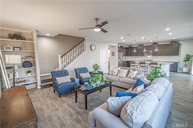 living room with crown molding, ceiling fan, and light hardwood / wood-style floors