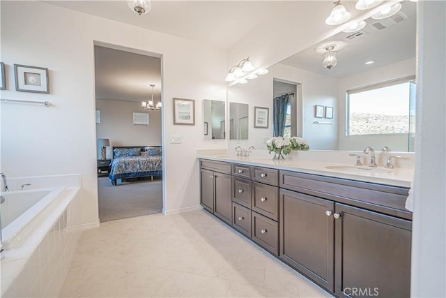 bathroom featuring tile patterned flooring, vanity, and tiled bath