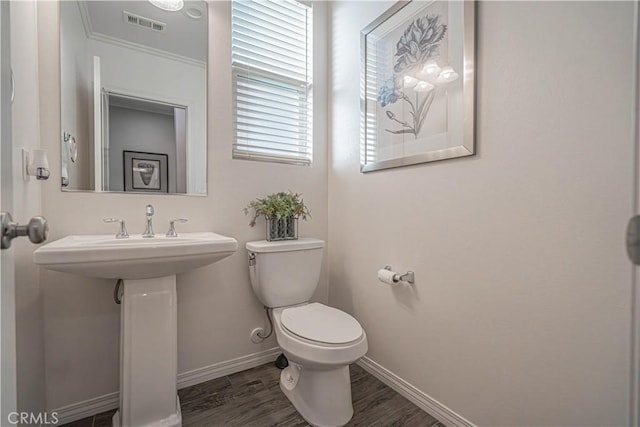 bathroom with hardwood / wood-style flooring, ornamental molding, and toilet