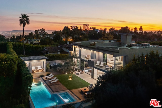 pool at dusk featuring an outdoor hangout area, a patio area, and a storage shed