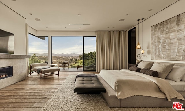 bedroom with access to outside, wood-type flooring, and a mountain view