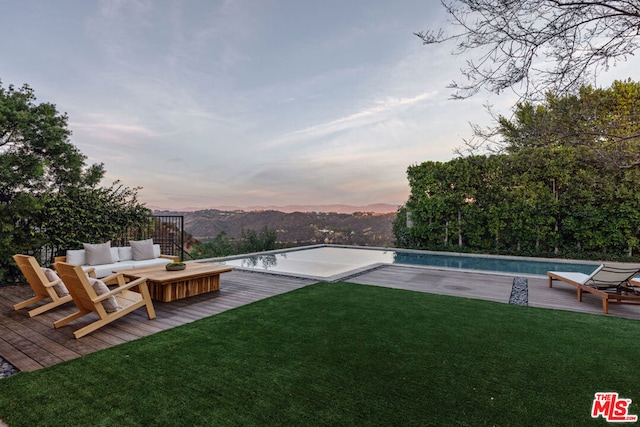 yard at dusk with an outdoor living space and a pool side deck