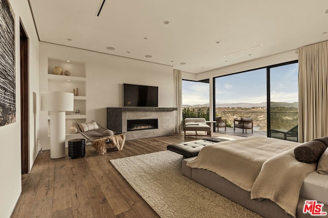 bedroom featuring expansive windows, access to exterior, and hardwood / wood-style floors