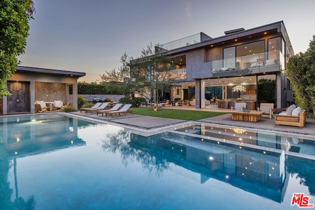 pool at dusk with an outdoor hangout area and a patio area