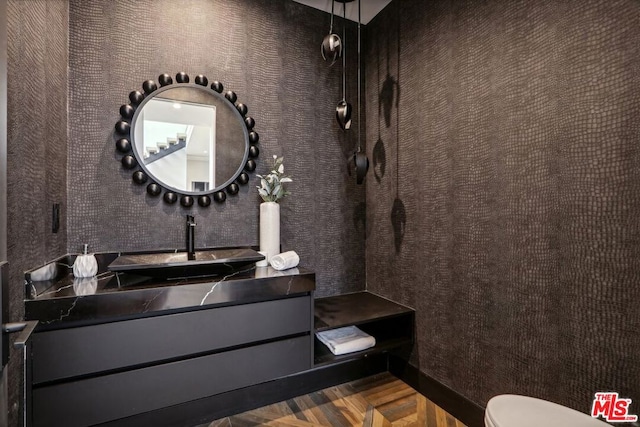 bathroom featuring toilet, vanity, and parquet floors