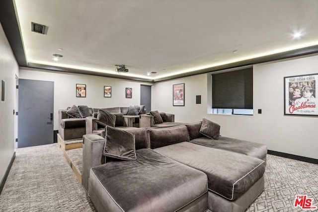 home theater room with a raised ceiling and light carpet