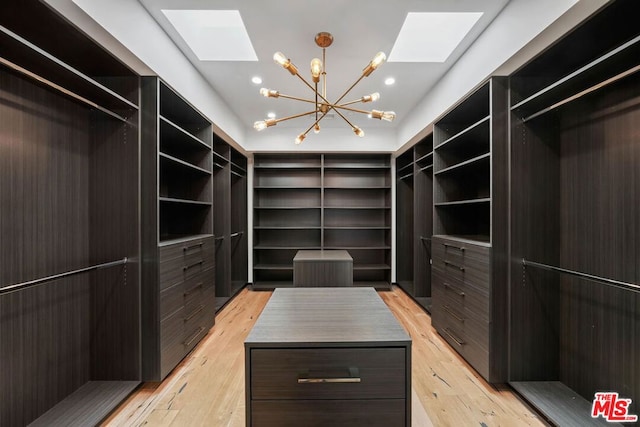 spacious closet featuring a skylight, a chandelier, and light hardwood / wood-style floors