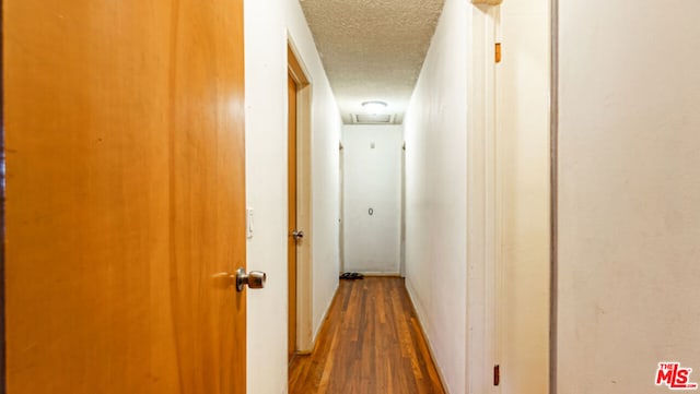 hall with wood-type flooring and a textured ceiling