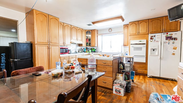 kitchen featuring white appliances, a center island, and hardwood / wood-style floors