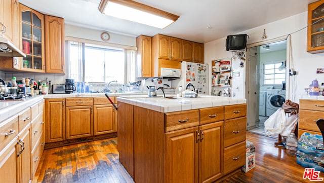 kitchen with independent washer and dryer, dark wood-type flooring, tile countertops, a center island, and white fridge