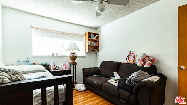 living room with a textured ceiling, ceiling fan, and hardwood / wood-style flooring