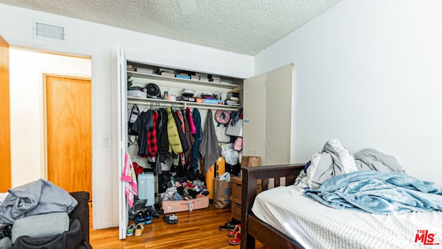 bedroom featuring wood-type flooring, a closet, and a textured ceiling