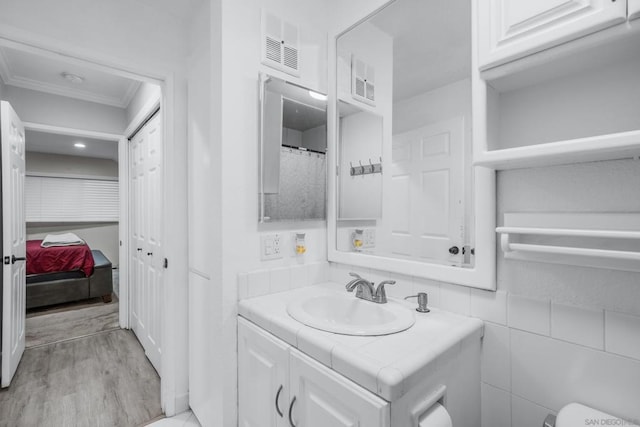 bathroom with crown molding, wood-type flooring, and vanity