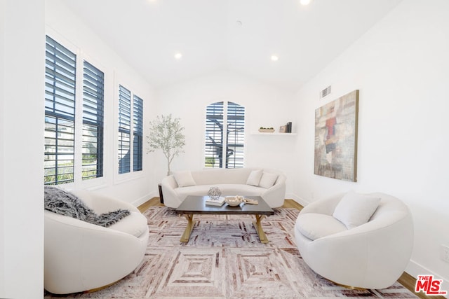 living room featuring lofted ceiling, light wood-type flooring, and plenty of natural light