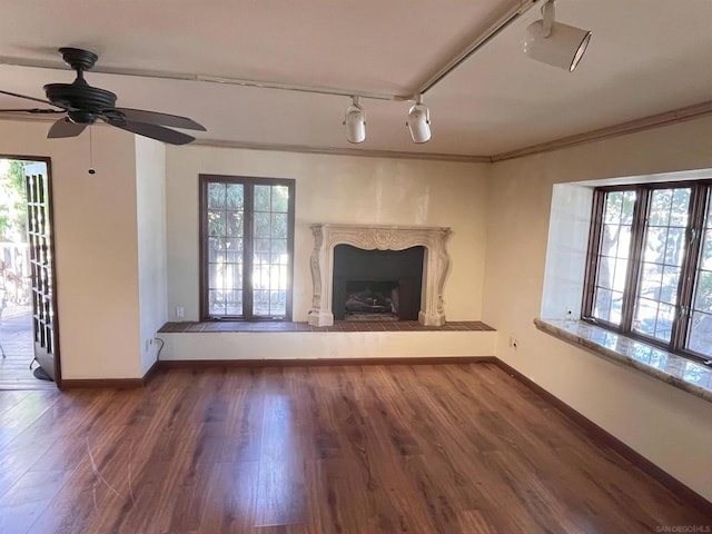 unfurnished living room featuring ceiling fan, dark hardwood / wood-style flooring, rail lighting, and ornamental molding